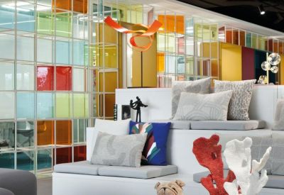 Lounge area featuring tiered white seating, colorful pillows, and decorative glass wall.