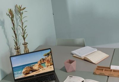 Close-up of a modern workstation with a laptop, notebooks, and decorative plants.