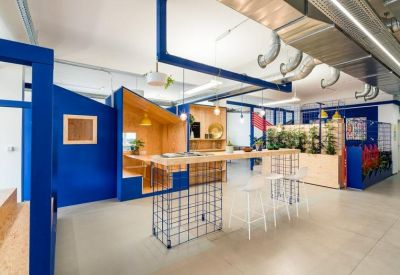 Bright communal break area featuring blue architectural structures and wooden bar seating.