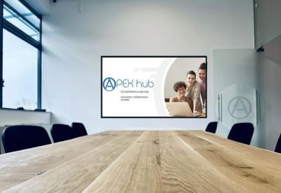 Modern boardroom with a large wooden table and a digital presentation screen.