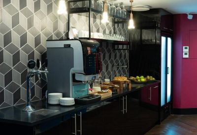 Communal kitchen and coffee station area with a geometric feature wall and dark wood finishes.