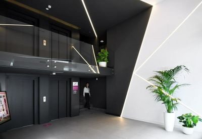 Sleek modern lobby with black walls, white geometric accents, and potted plants.