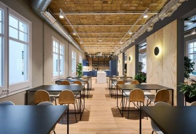Long dining area with wooden tables, brick vaulted ceilings, and large windows.