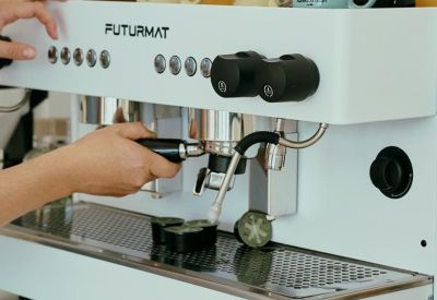 Close-up of a professional white espresso machine with yellow coffee mugs.