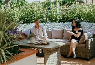 Outdoor patio with comfortable seating and a large beige sun umbrella.