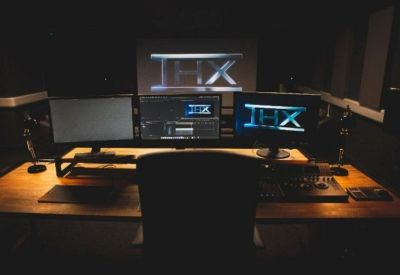 Triple monitor workstation on a wooden desk with a black office chair.
