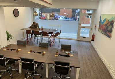 Open-plan coworking area with wooden desks, office chairs, and wall art.