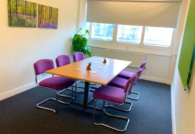 Bright meeting room with purple chairs, a large window, and vibrant nature photography.