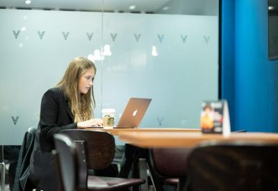 Individual workspace at a wooden table against a glass partition.