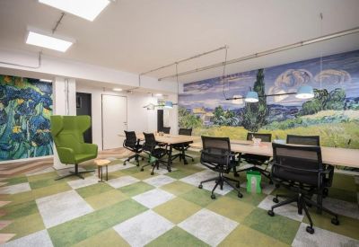 Spacious meeting room with a nature-inspired mural, green checkered carpet, and a large conference table.