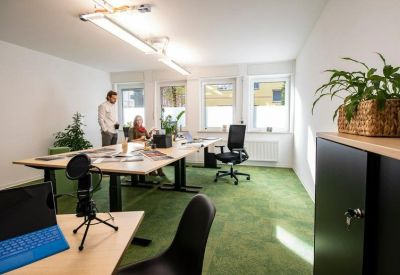 Bright coworking area with green flooring, indoor plants, and a collaborative workbench.