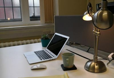 Private workstation with a laptop, lamp, notepad, and view through a classic window.