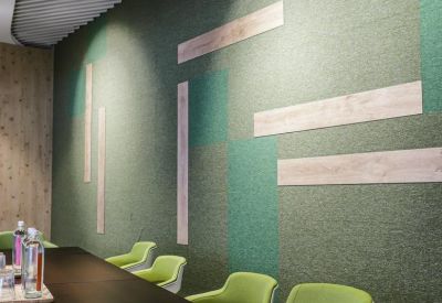 Close-up of a decorative office wall with green acoustic paneling and horizontal light wood accents.