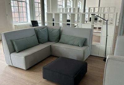Lounge area with a grey sectional sofa, green pillows, and a white room divider.