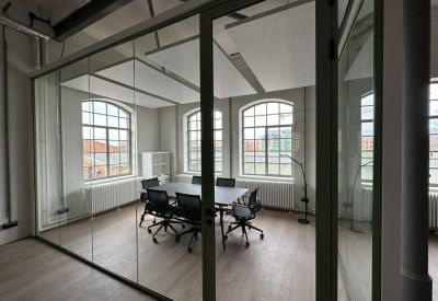 Glass-walled conference room with a large table, black chairs, and arched windows.