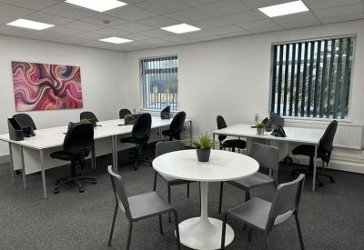 Bright coworking space with white desks and a round central meeting table.