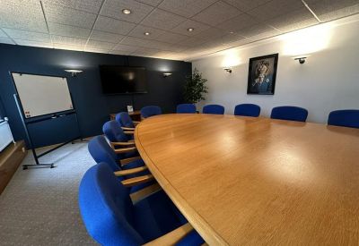 Conference room featuring an oval wooden table and blue upholstered chairs.
