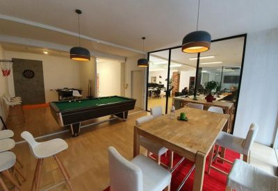 Communal breakout area featuring a pool table, dining table, and red rug.