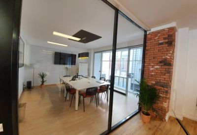 Glass-walled meeting room with a large white table and brick accents.