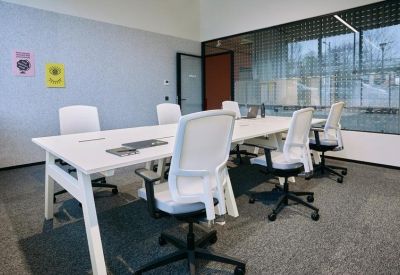 Bright meeting room with a large white table and white ergonomic chairs.