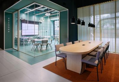 Sleek glass-walled meeting pod and a long wooden communal table with modern chairs.