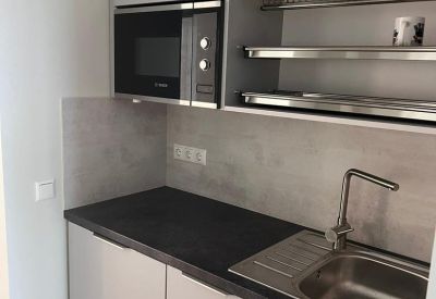 Modern compact kitchenette with grey cabinetry and integrated microwave.