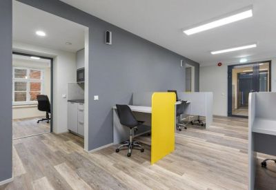 Open-plan office space featuring desks with yellow privacy dividers and wooden floors.