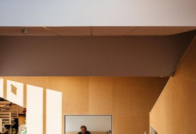 Waiting area with orange velvet armchairs and a view into a bright office space.