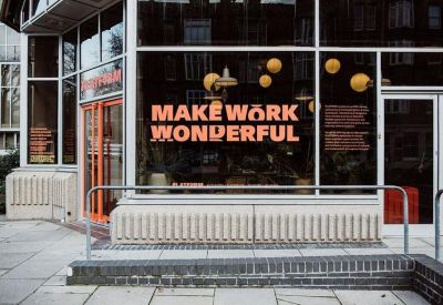 Exterior entrance of the building featuring large glass windows and Make Work Wonderful signage.