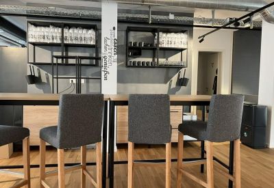 Modern kitchen and bar area with high chairs and wood flooring.