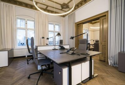 Bright private office with parquet floors, high ceilings, and shared desks.