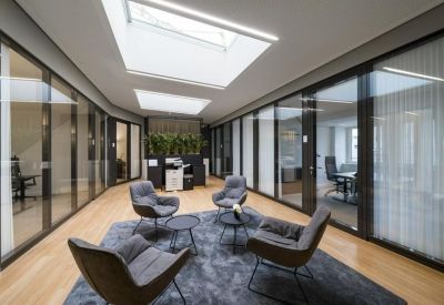 Central meeting hub with grey armchairs under bright skylights.