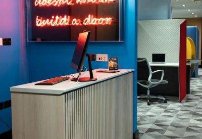 Modern reception desk at Lakeshore Drive, Portsmouth featuring a vibrant blue wall and neon quote sign.