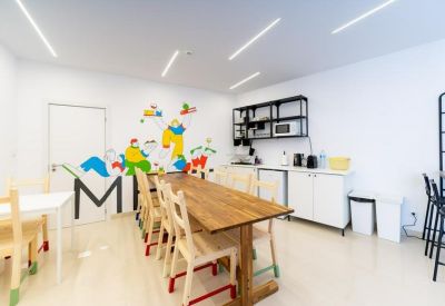 Communal kitchen and dining area with a long wooden table and colorful wall art.
