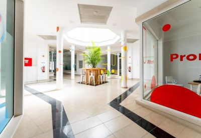 Bright white lobby with central planters, white columns, and red accents.