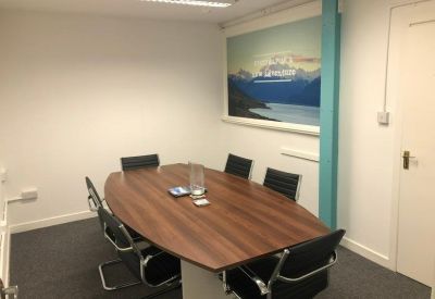 Boardroom featuring an oval wooden table, black leather chairs, and a scenic wall mural.