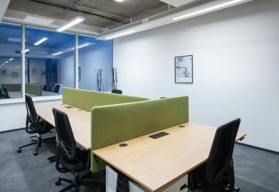 Bright open-plan workspace with wooden desks and green acoustic privacy dividers.
