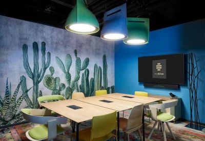 Creative meeting room with a cactus-themed mural and vibrant yellow and green seating.