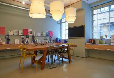Sunlit meeting room with a large wooden table, designer chairs, and oversized pendant lights.