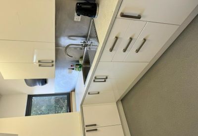 Compact modern kitchenette with white cabinetry and a stainless steel sink.