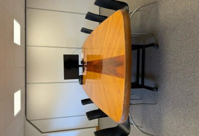 Spacious boardroom featuring a polished wood table and black leather chairs.
