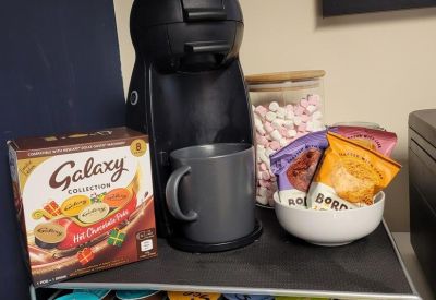 Coffee and hot chocolate station with various pods and snacks.