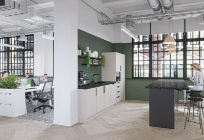 Modern communal kitchen and breakout area with a green feature wall, island seating, and industrial ceiling.