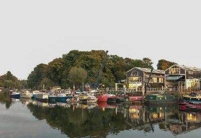 Scenic view of a river with numerous boats moored alongside a wooded bank.
