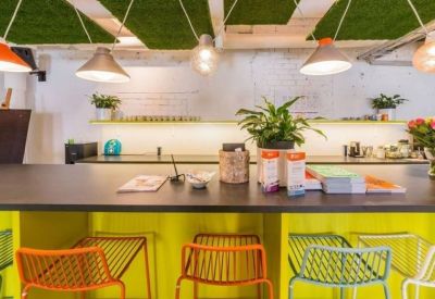 Communal kitchen area with a yellow breakfast bar, colorful stools, and hanging pendant lights.