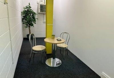 Small break area with a round bistro table, two chairs, and a yellow pillar.