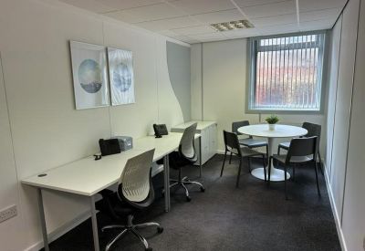 Private office featuring white desks and a small round meeting table.