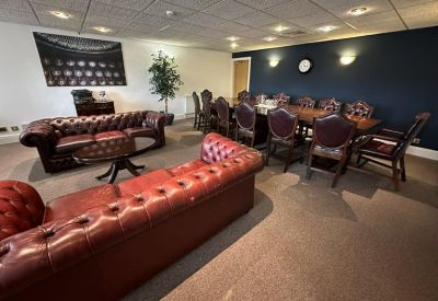 Executive boardroom with a long mahogany table, leather chairs, and a navy feature wall.