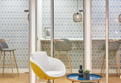 Sleek seating area with grey and yellow chairs separated by glass partitions with geometric patterns.