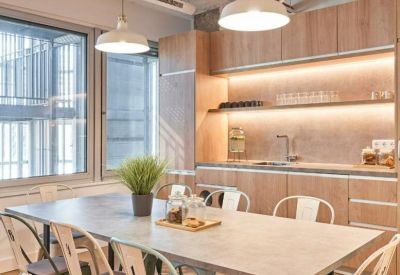 Bright shared kitchen and dining area with wooden cabinetry and industrial-style pendant lighting.